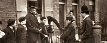 Italian child playing a harp to a small crowd